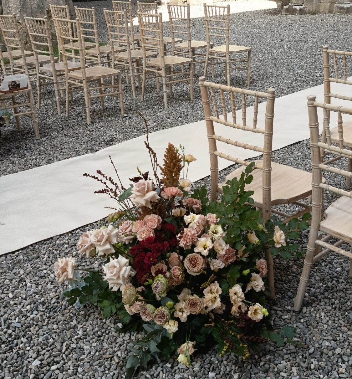 Weißer Läufer und Stühle mit elegantem Blumengesteck für eine Hochzeit in der Toskana